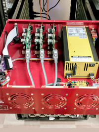 Open red electronics case displaying internal yellow power supply, green circuit boards, and gray data cables.